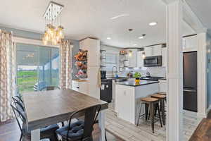 Kitchen featuring dishwasher, dark countertops, a textured ceiling, and white cabinetry