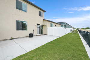 Back of property with a yard, stucco siding, fence, and a patio