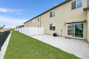 Back of house featuring a patio, stucco siding, a fenced backyard, cooling unit, and a lawn