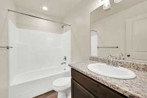 Full bath featuring toilet, wood finished floors, bathing tub / shower combination, visible vents, and vanity