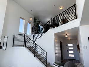 Stairway featuring baseboards, a towering ceiling, and visible vents