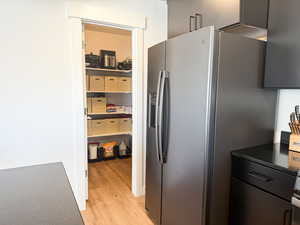 Interior space with stainless steel fridge, light wood-type flooring, and dark countertops