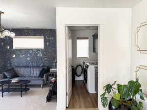 Washroom with wallpapered walls, wood finished floors, washer and dryer, and laundry area