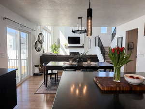 Dining area with a notable chandelier, wood finished floors, a textured ceiling, and stairway
