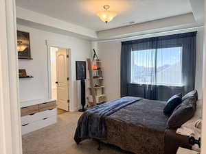 Bedroom with light carpet, a textured ceiling, and visible vents