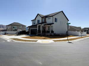 Traditional-style house featuring an attached garage, concrete driveway, and fence