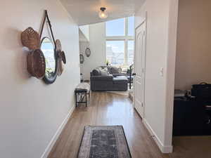 Corridor featuring wood finished floors, a textured ceiling, and baseboards