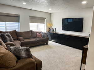 Living room featuring recessed lighting, a textured ceiling, visible vents, and light carpet