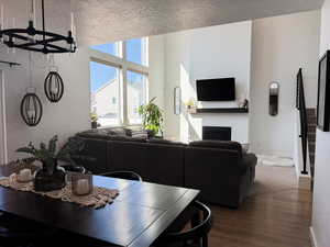 Dining area featuring a textured ceiling, baseboards, a chandelier, wood finished floors, and a fireplace