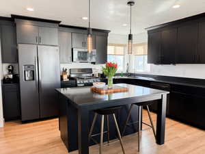 Kitchen with a sink, a textured ceiling, dark countertops, a breakfast bar, and appliances with stainless steel finishes