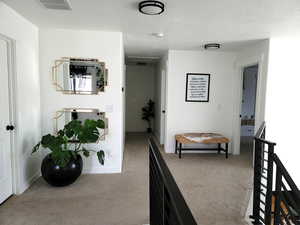 Hallway featuring baseboards, visible vents, carpet, and a textured ceiling