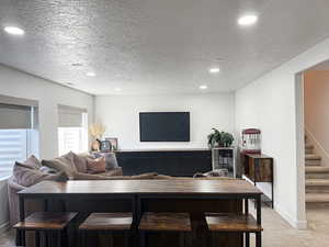 Living room featuring recessed lighting, carpet floors, baseboards, and stairs