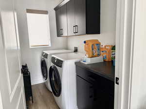 Washroom featuring baseboards, cabinet space, washer and clothes dryer, and light wood-type flooring