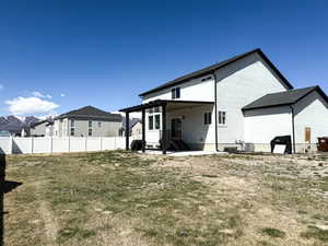 Back of property with a lawn, a pergola, and fence
