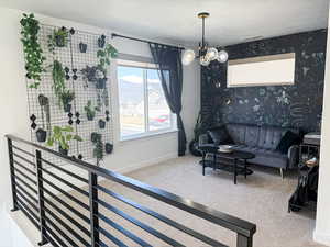 Carpeted living room with wallpapered walls, baseboards, a textured ceiling, and a chandelier