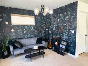 Carpeted living room featuring wallpapered walls, visible vents, an inviting chandelier, and a textured ceiling