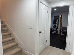 Corridor featuring stairway and carpet
