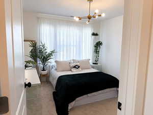 Carpeted bedroom featuring a notable chandelier