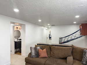 Living room featuring visible vents, recessed lighting, a textured ceiling, and light colored carpet