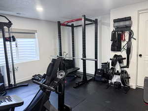 Workout room with baseboards, a textured ceiling, and visible vents