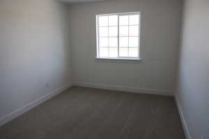 Unfurnished room with baseboards and dark carpet
