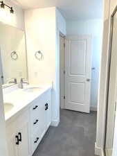 Bathroom featuring a shower stall, baseboards, a sink, and double vanity