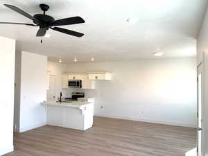 Kitchen with a peninsula, baseboards, stainless steel appliances, and a sink