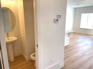 Half bathroom featuring visible vents, baseboards, wood finished floors, and toilet