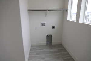 Washroom featuring hookup for an electric dryer, baseboards, washer hookup, wood finished floors, and laundry area