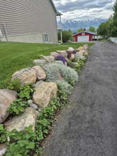 View of property exterior with an outdoor structure, a lawn, a mountain view, and a garage