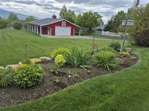 View of yard featuring driveway, a detached garage, and an outbuilding