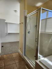 Primary bathroom featuring a shower stall, tile floors, separate garden tub, and walk-in closet