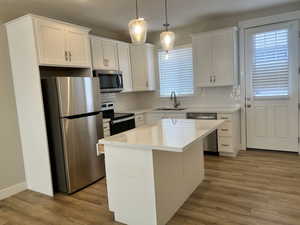 Kitchen featuring white cabinets, backsplash, appliances with stainless steel finishes, and a sink