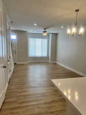 Interior space featuring baseboards, recessed lighting, wood finished floors, and ceiling fan with notable chandelier