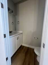 Bathroom with baseboards, wood finished floors, toilet, and vanity