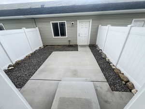 Entrance to property with a patio, a shingled roof, and fence