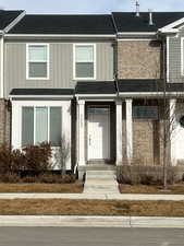 View of front of home featuring roof with shingles, board and batten siding, and brick siding
