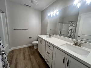 Bathroom with toilet, a sink, wood finished floors, and visible vents