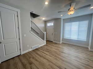 Unfurnished living room with visible vents, stairway, ceiling fan, and baseboards