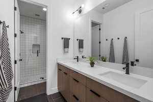 Full bath with double vanity, a shower stall, visible vents, and a sink