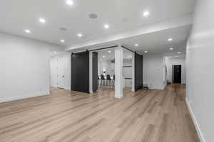 Lower level featuring a barn door, light wood-type flooring, and baseboards