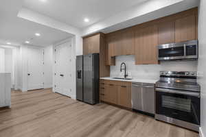 Kitchen featuring stainless steel appliances, a sink, light wood-type flooring, recessed lighting, and light countertops