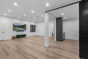 Lower level area with light wood finished floors,  recessed lighting, and a barn door