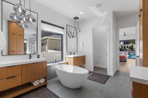 Primary Bedroom with Ensuite bathroom featuring tile patterned floors, a soaking tub, two vanities, and a sink