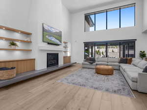 Living room with a glass covered fireplace, hardwood / wood-style flooring, and a towering ceiling