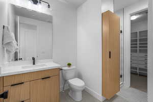 Full bath with tile patterned flooring, toilet, vanity, baseboards, and a stall shower