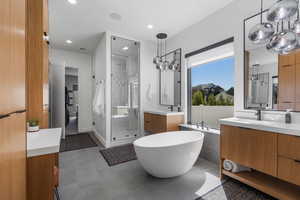 Primary Bathroom featuring two vanities, a sink, a freestanding bath, a stall shower, and recessed lighting