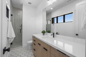 Full bath featuring toilet, vanity, tile patterned floors, and a stall shower