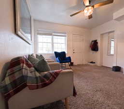Carpeted living room with ceiling fan and a healthy amount of sunlight