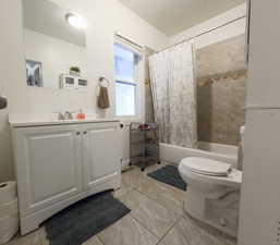 Full bath featuring vanity, tile patterned flooring, shower / bathtub combination with curtain, and toilet